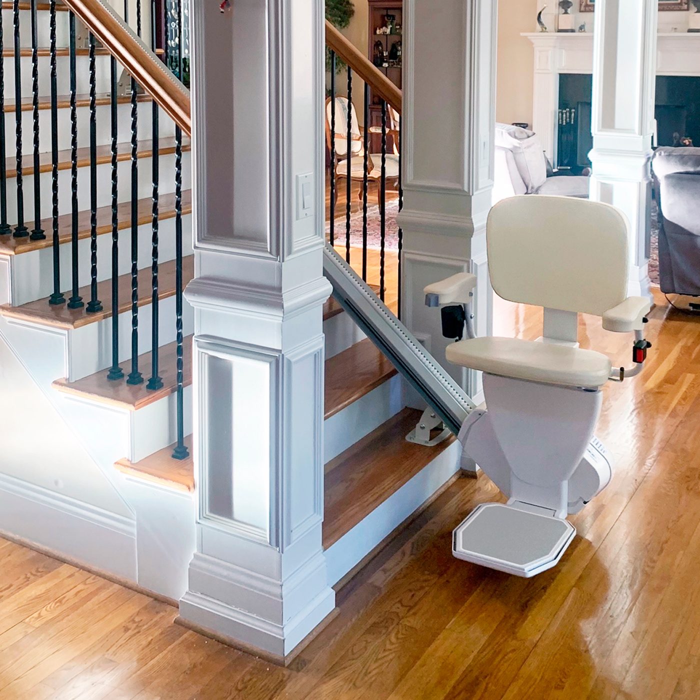 AmeriGlide stairlift shown from the rear, parked at the bottom of a staircase with white balusters