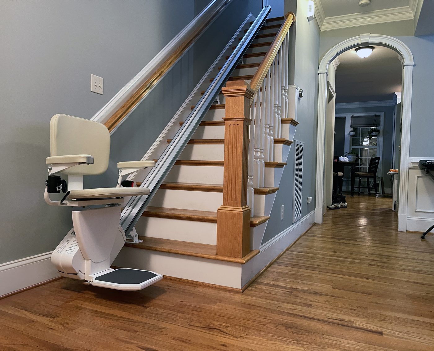 AmeriGlide stairlift parked at the base of a staircase with wrought iron balusters